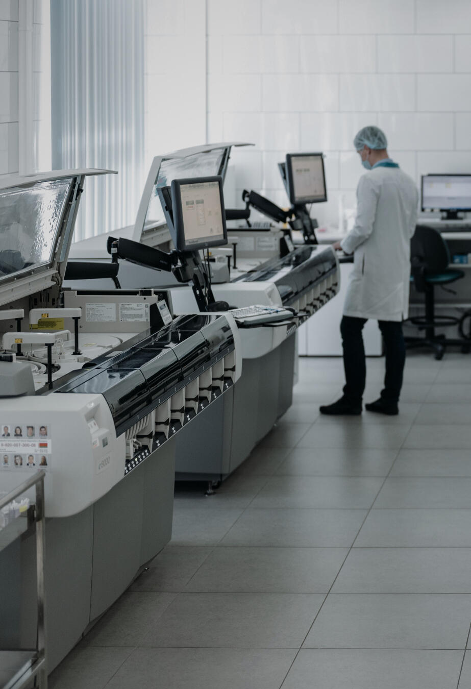 Laboratory technician operating diagnostic machines in a modern clinical lab setting at Health Stat. Photo of a modern diagnostic laboratory with a technician operating high-end analyzers, representing Health Stat's send-out lab services